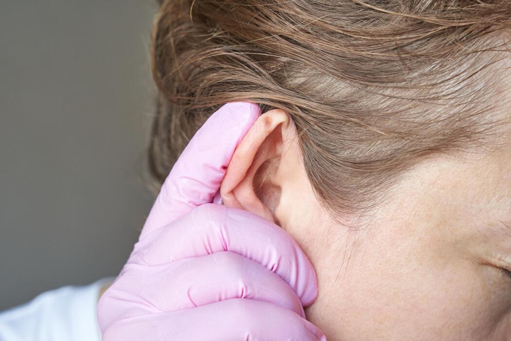 close-up-of-female-adult-with-caucasian-skin-having-ear-examined-by-doctor-wearing-pink-gloves-photo